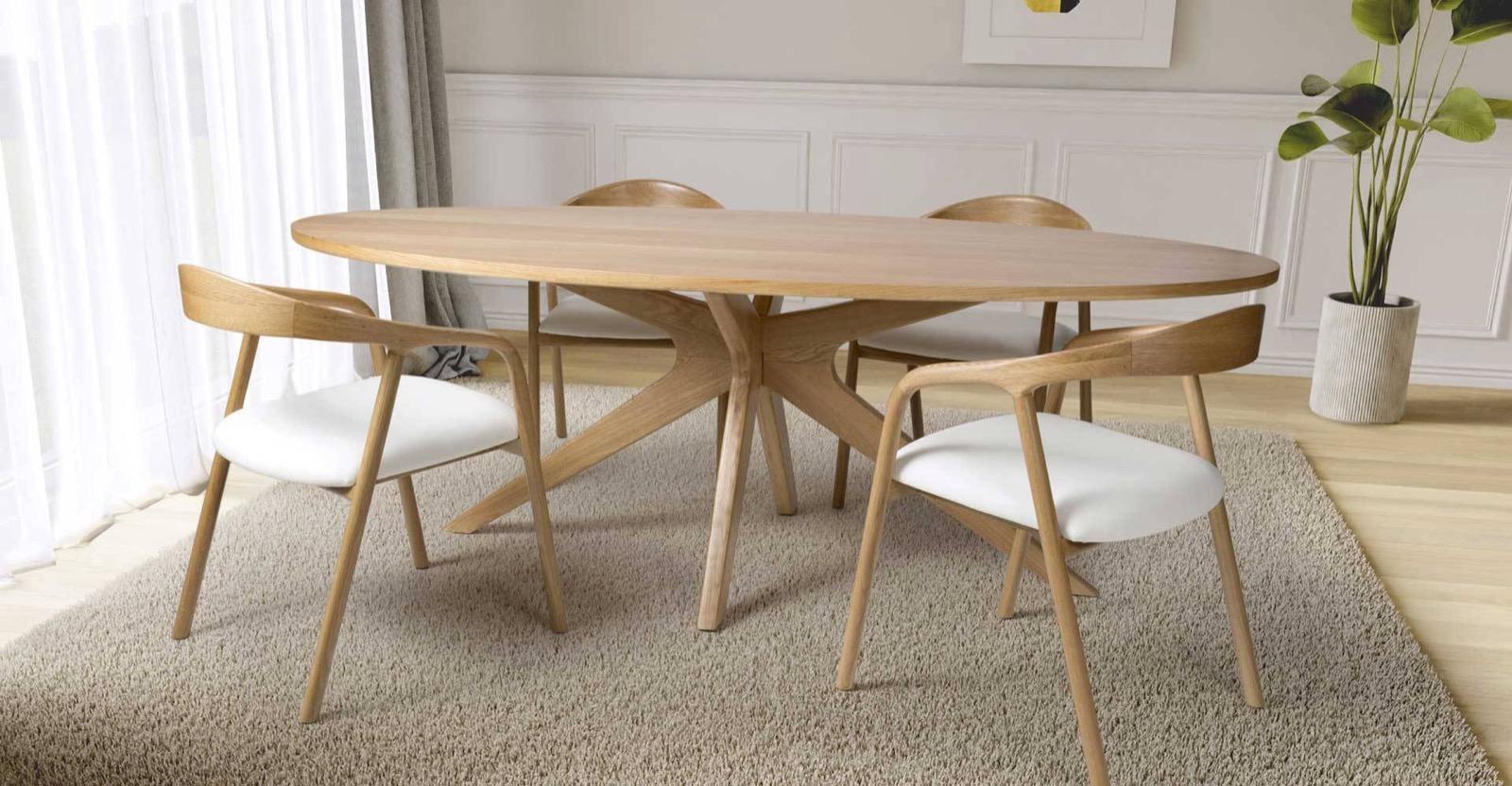 An oval oak dining table and curved chairs on a rug in a bright, panelled dining room.
