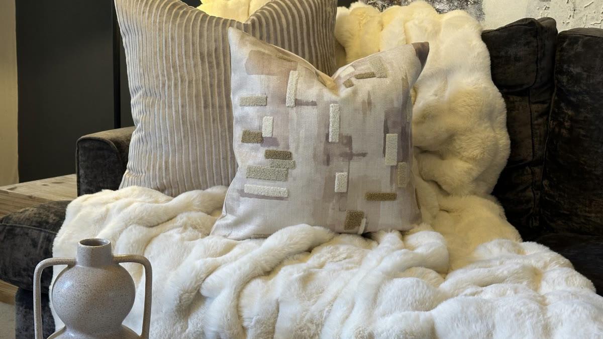 Malini cushions in oatmeal and pale linen on a faux-fur throw, with stoneware vases alongside