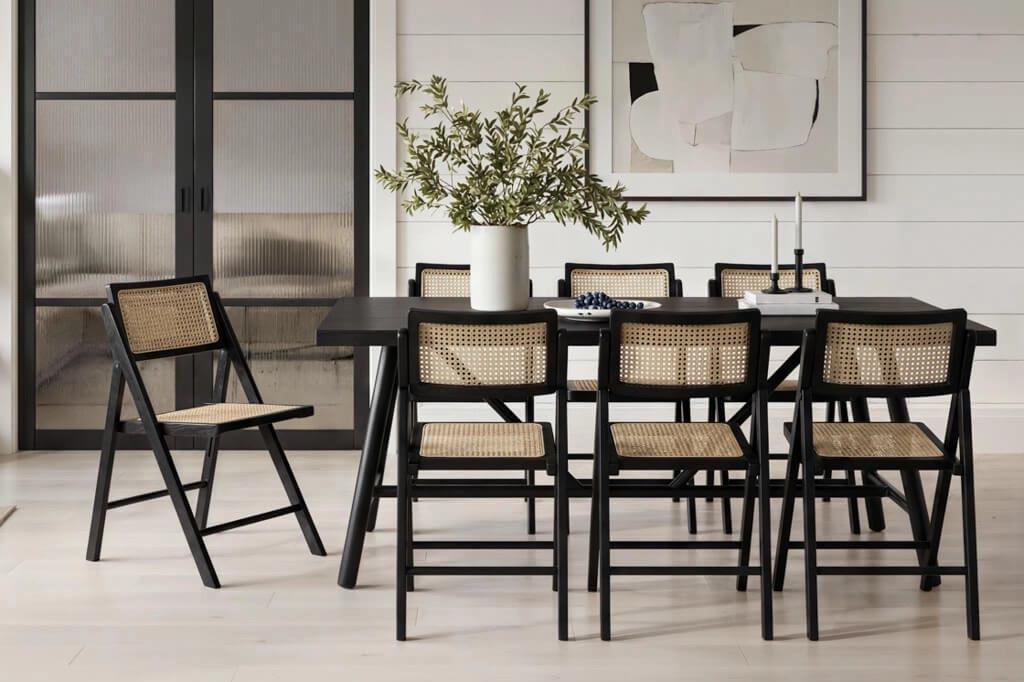 An LPD Ashton black dining table with cane-backed folding chairs in a bright panelled room