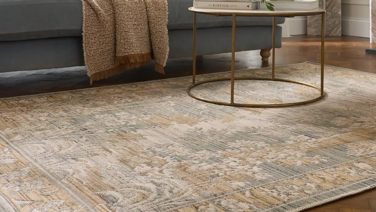 A Think Rugs antique-wash rug in sage and gold, under a brass coffee table