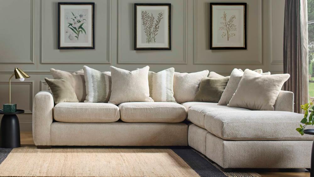 A Buoyant Montana corner sofa in cream bouclé, with botanical prints above a panelled wall
