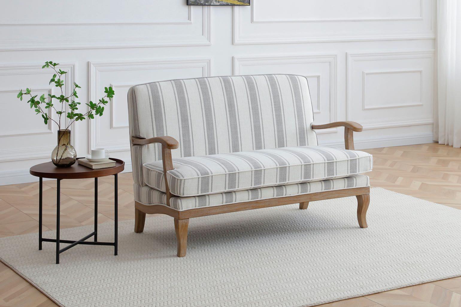 A Kyoto Colwell two-seater sofa in grey ticking stripe with a limed oak frame, on a herringbone floor