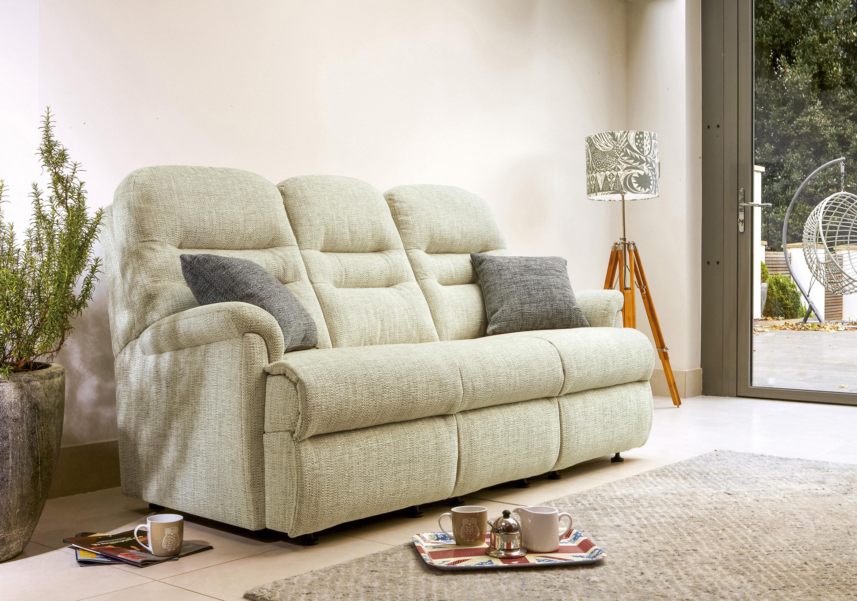 A cream Sherborne Keswick reclining three-seater sofa in a bright room opening onto a garden