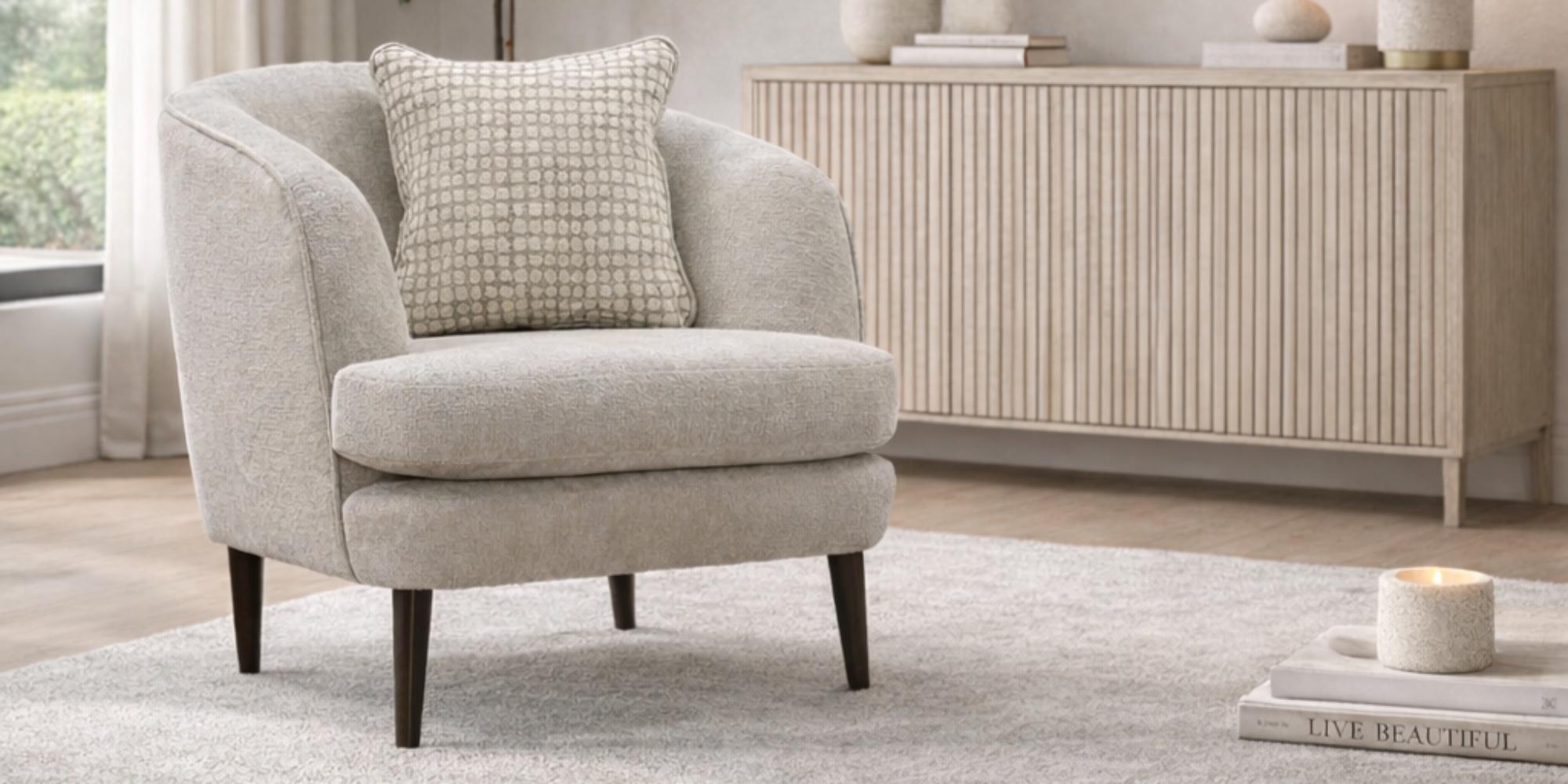 An oatmeal Buoyant Nora accent armchair with a textured scatter cushion, on a soft rug beside a fluted sideboard.