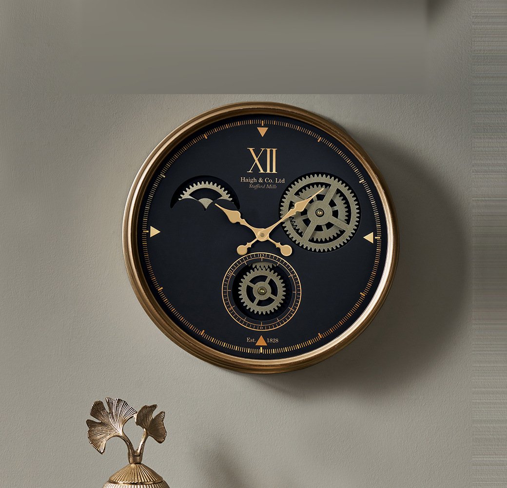 A cog clock hung on a wall, a navy dial in a brass case with exposed gears turning at its centre