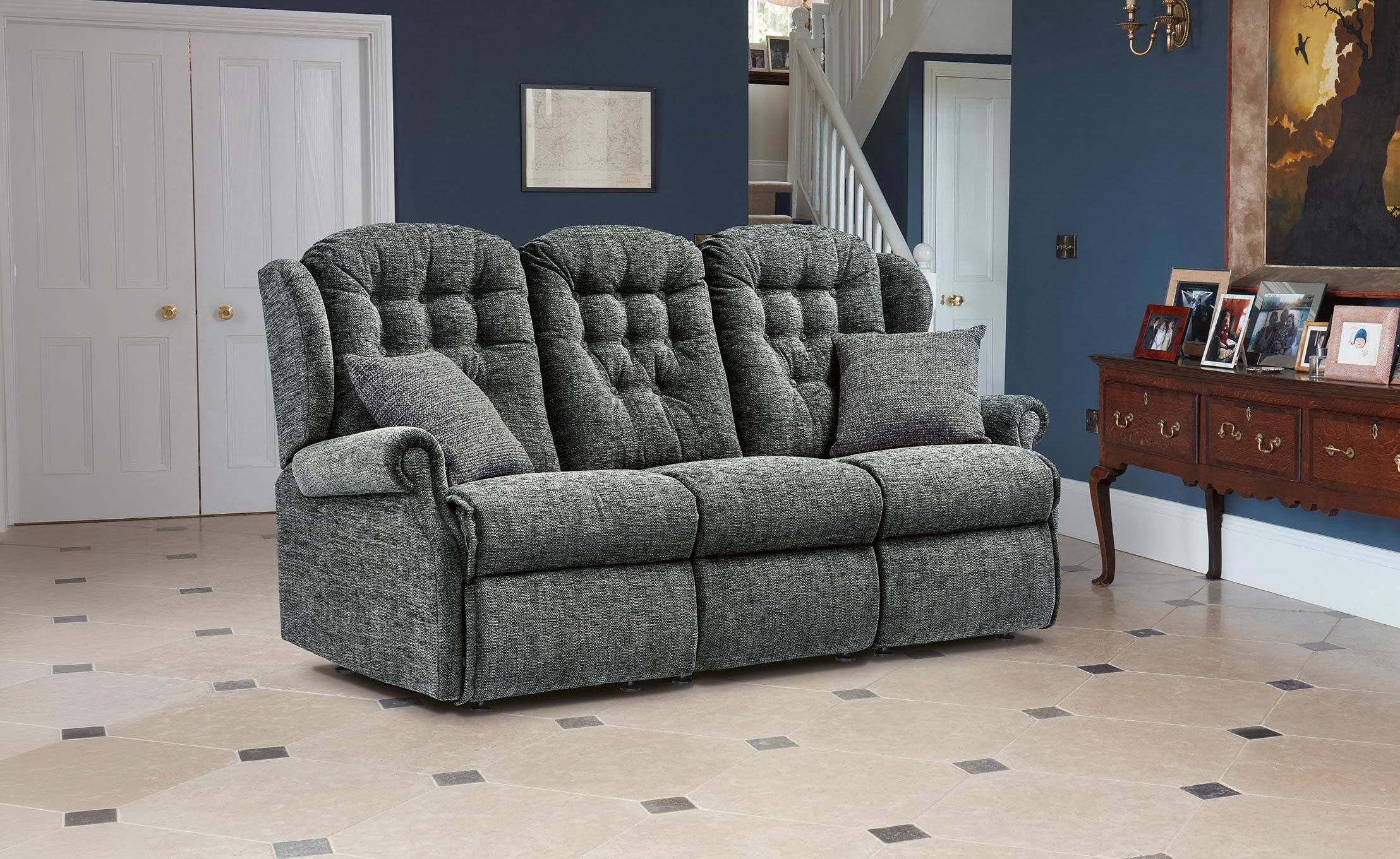 A Sherborne Lynton three-seater settee in charcoal fabric, beside an oak sideboard in a deep-blue panelled hallway