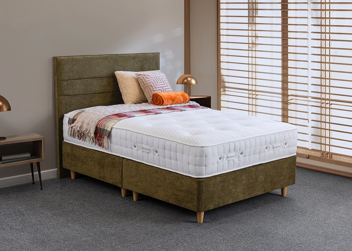 A Sweet Dreams mattress on an olive-green divan, warmly dressed in a calm bedroom